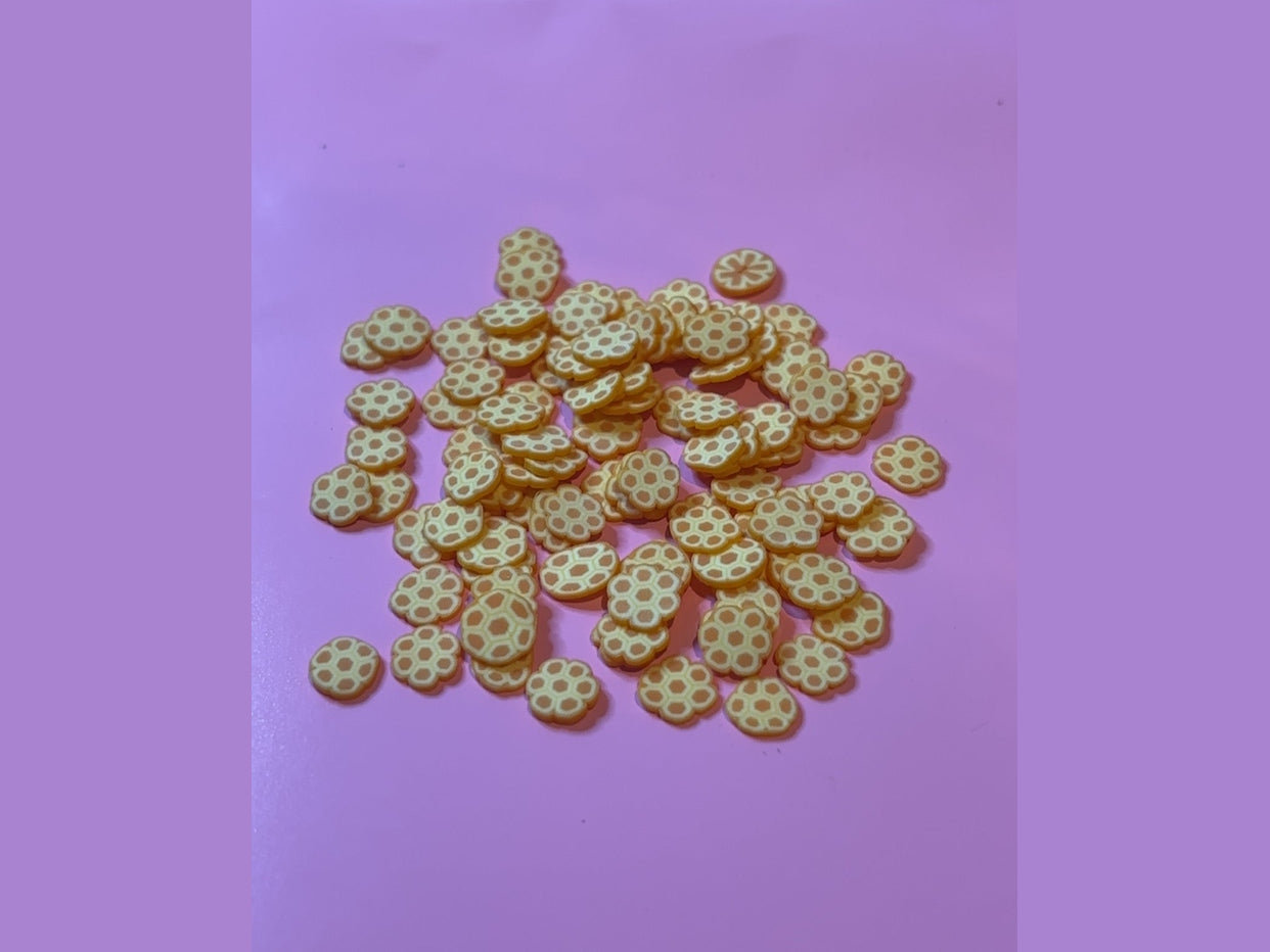 Light yellow honeycomb shaped candy pieces on pink background