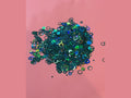 Dark green iridescent glitter bubble rings with blue and gold highlights on pink background