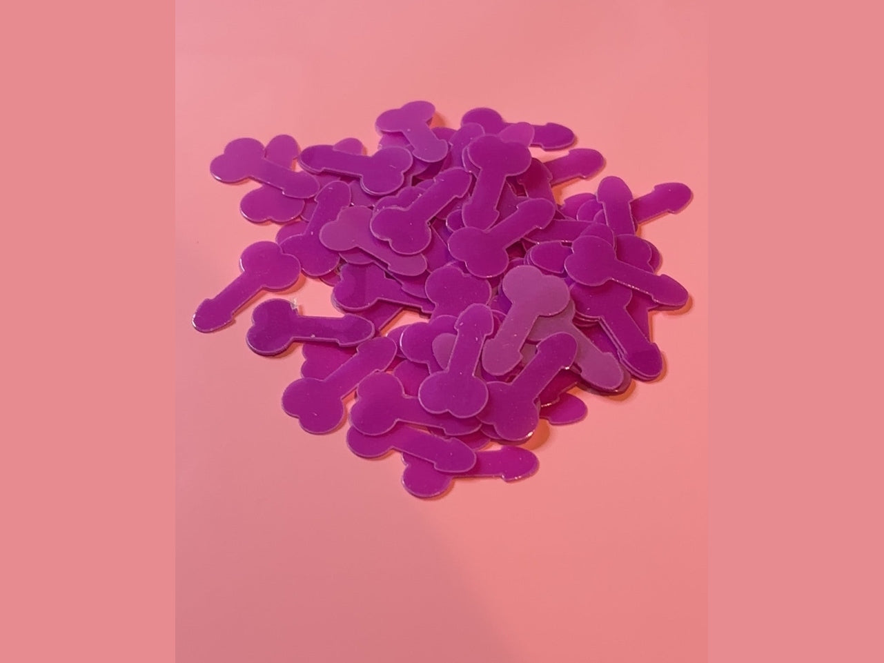 Little Richards purple glow in the dark bone-shaped confetti on pink background