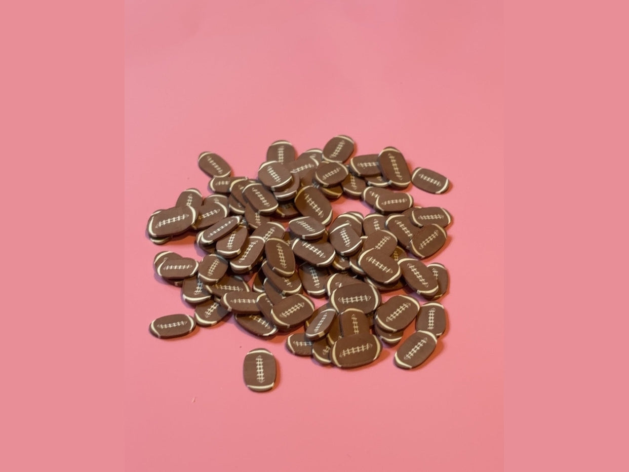 Brown oval American footballs with white lacing and stripes on pink background