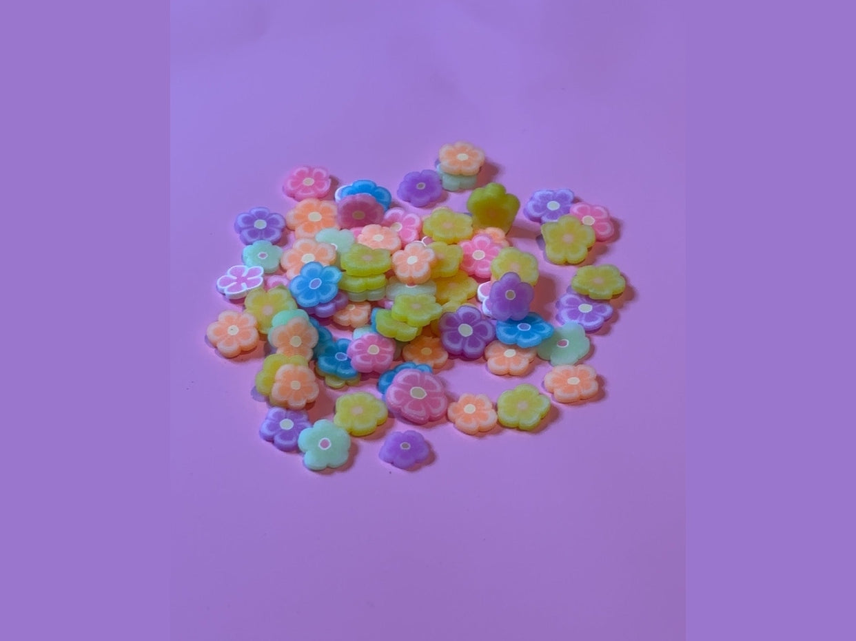 Pastel and bright flower-shaped charms with white centers on purple background