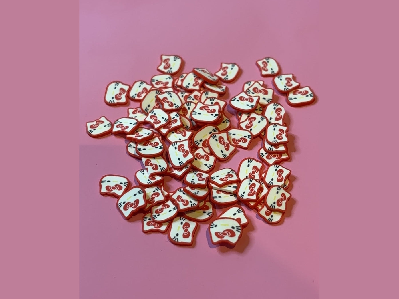 Hello Kitty polymer clay pieces with red bow and white face on pink background