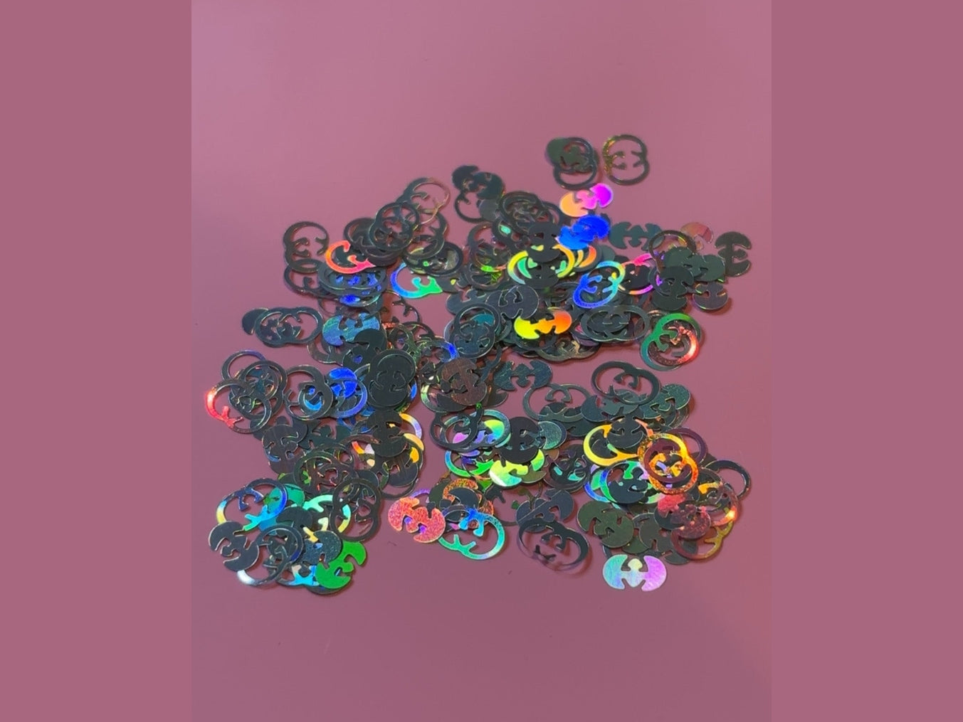 GG Glitter Shape black holographic interlocking G logo craft pieces on pink background