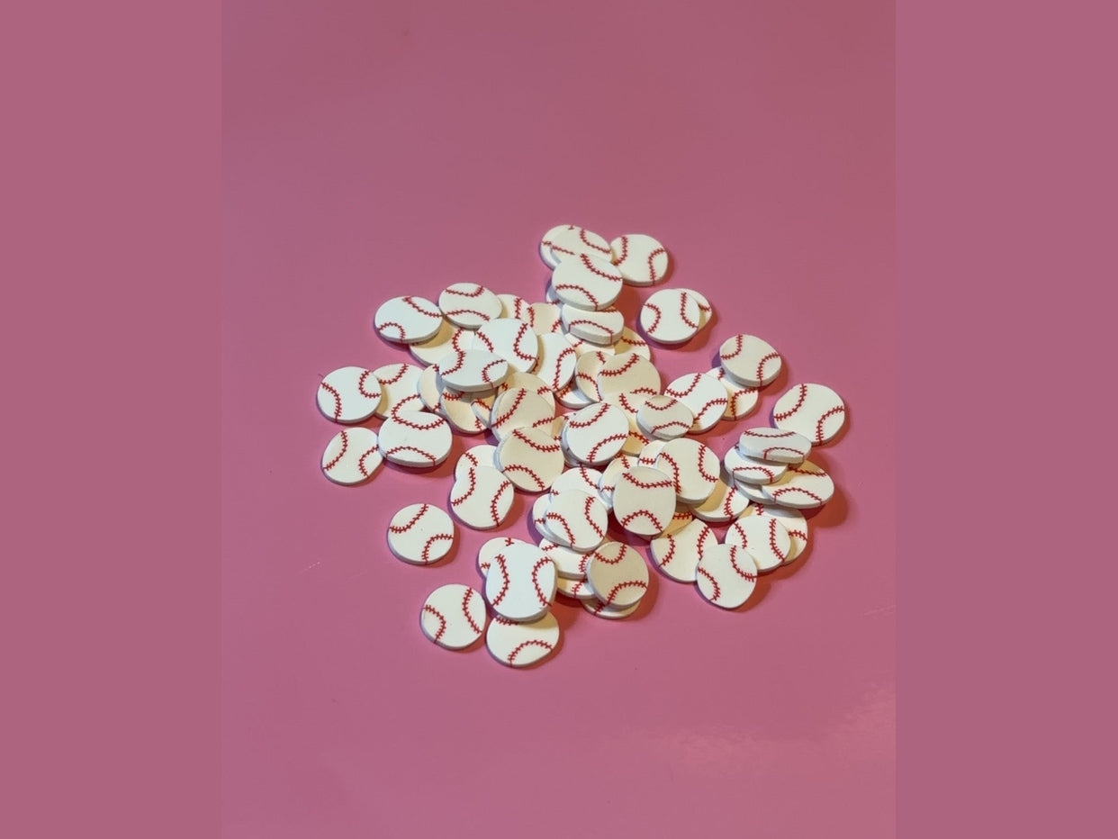 White baseball clay pieces with red stitched seams on pink background