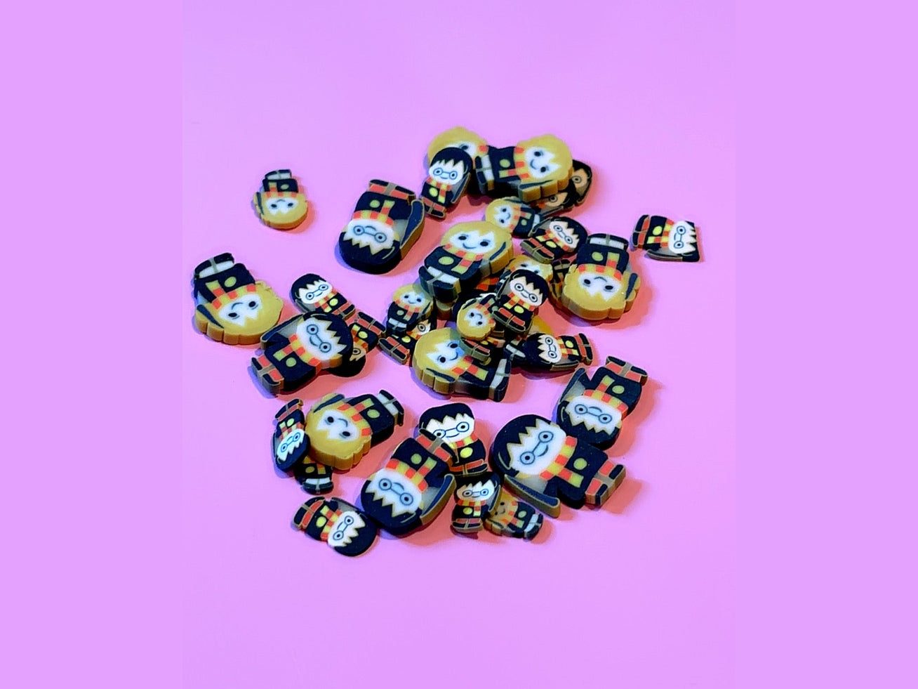 Harry Potter Gryffindor figurines with yellow heads and black robes on pink background