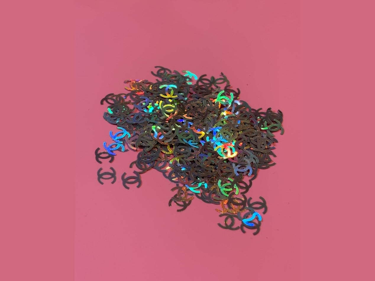CC Glitter Shape metallic holographic interlocking logo cutouts on pink background