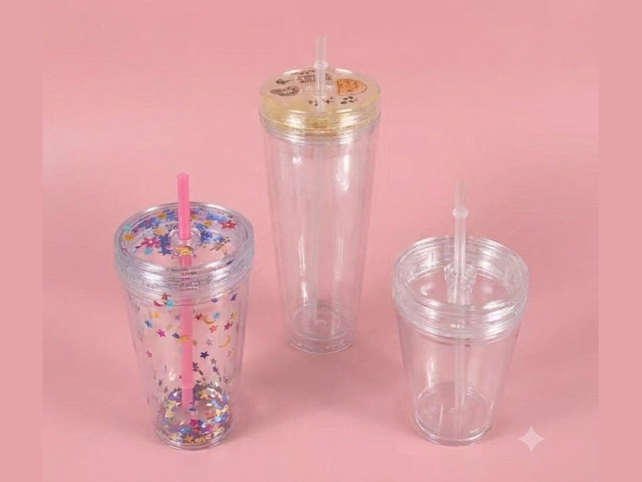 Three 16oz double lid tumblers with star confetti, gold and clear lids, and straws on pink background