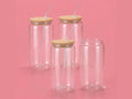 Four clear 16oz glass tumblers with bamboo lids and straws on pink background