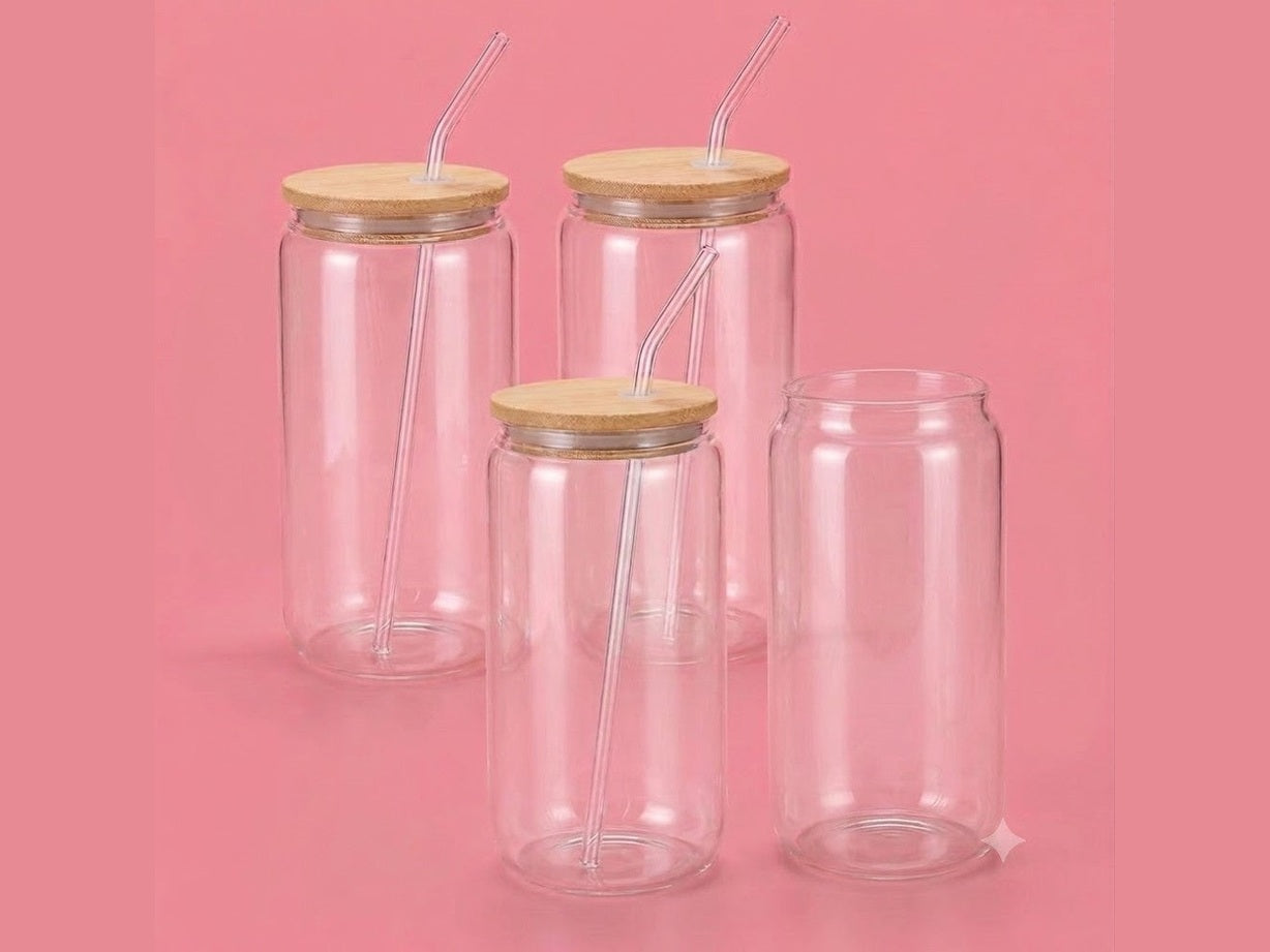 Four clear 16oz glass tumblers with bamboo lids and straws on pink background