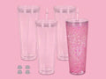 Four 24oz clear double-walled tumblers with white straws and pink glitter liquid on pink background